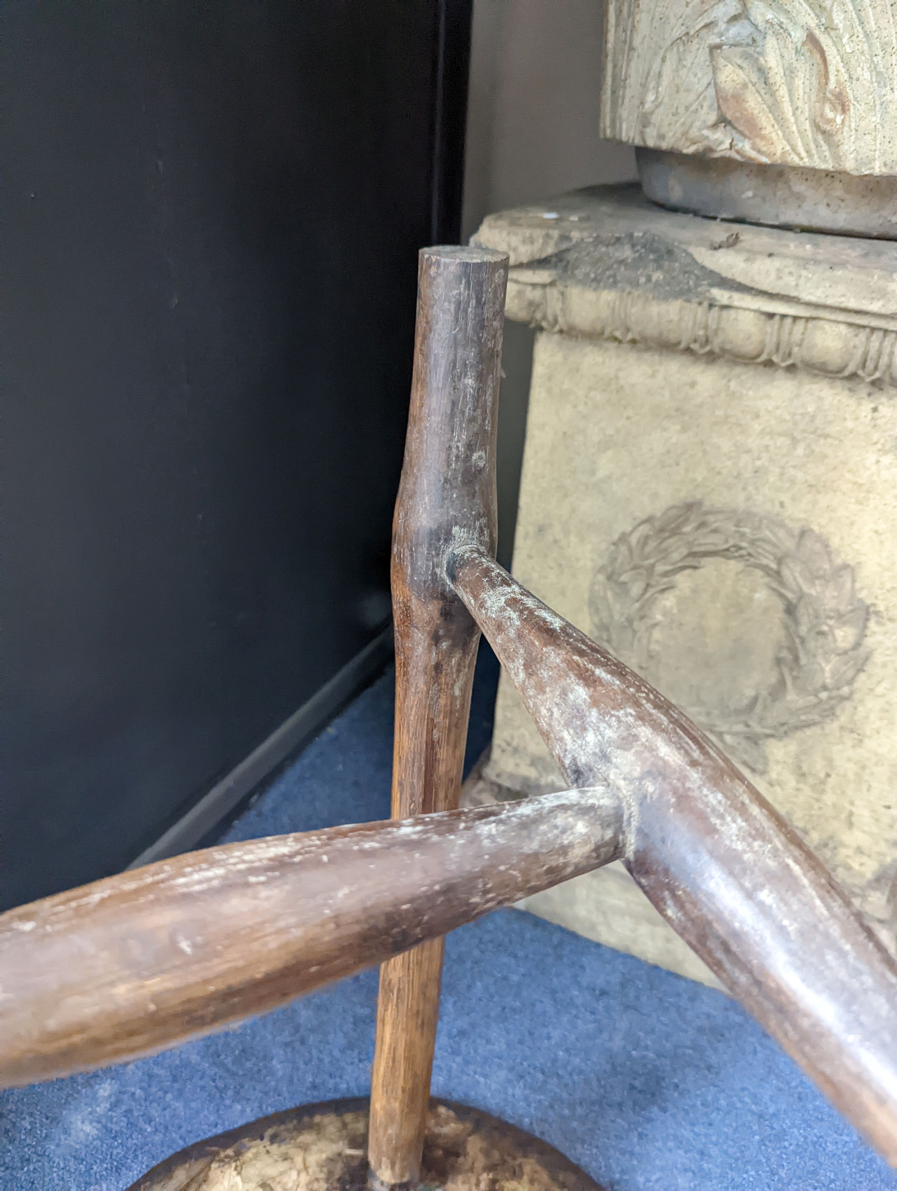 A circular burr elm and ash primitive cricket table with T shaped stretcher, diameter 44cm, height 61cm